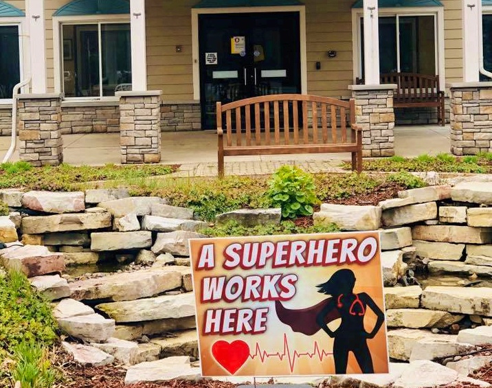 Assisted Living and Covid-19. Yard sign in front of building that says A super hero works here
