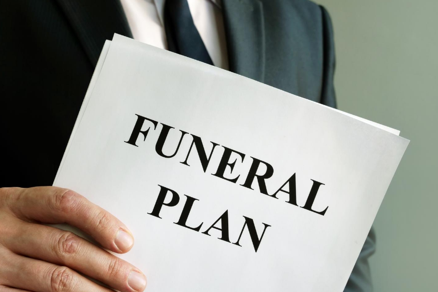 Losing Someone to Covid-19. Man holder a folder with the words Funeral Plan on it